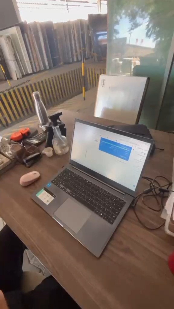 Notebook com o painel aberto no pátio coberto, com as chapas nos cavaletes ao fundo